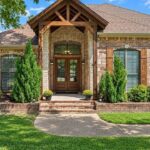 Brick and stone home with a timber-framed front entry and landscaped walkway in Lindale, Texas