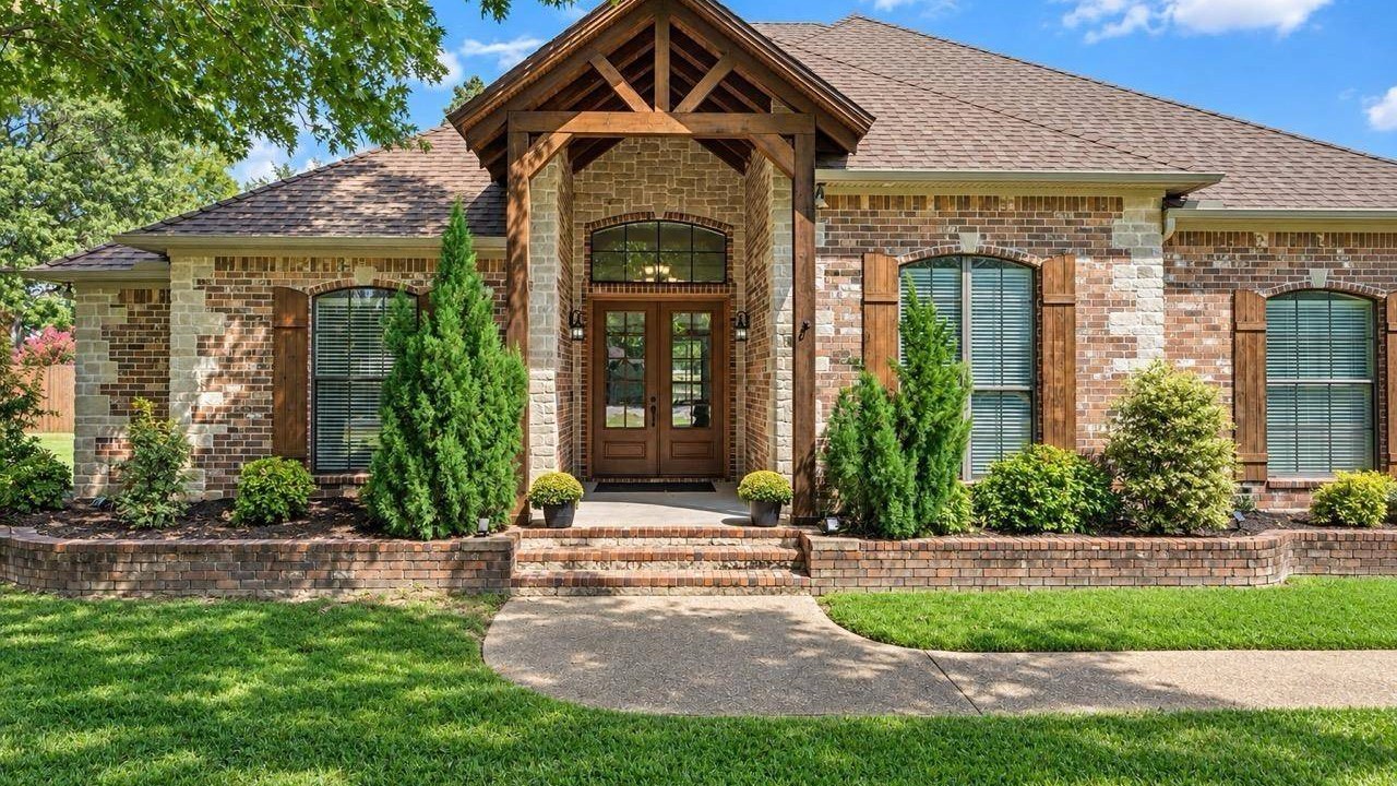 Brick and stone home with a timber-framed front entry and landscaped walkway in Lindale, Texas